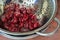 Fresh thawed seedless cherries in a metal colander