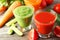 Fresh tomate, carrot and cucumber juice on grey wooden background.