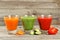 Fresh tomate, carrot and cucumber juice on grey wooden background