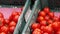 Fresh tomatoes are in plastic crates in the vegetable section of the supermarket