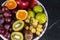 Fresh tropical fruitson in bowl on black marble background.