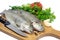 Fresh trout on wooden board with parsley, garlic, tomato, pepper and knife