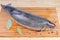 Fresh uncooked arctic char on wooden cutting board with spices