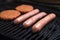 Fresh uncooked barbecue sausages, burgers and bread