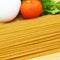 Fresh uncooked gold colored pasta, tomatoes, egg, parsley