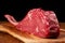 Fresh uncooked tomahawk steak on the bone on wooden cutting board and table and black background. Prime cut of beef. High quality