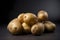 Fresh, unpeeled potatoes on a grey background. The potatoes are arranged naturally, forming a small stack.