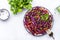 Fresh vegan coleslaw salad with red cabbage, carrot, parsley and olive oil dressing on white kitchen table background, top view