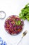 Fresh vegan coleslaw salad with red cabbage, carrot, parsley and olive oil dressing on white kitchen table background, top view
