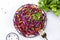 Fresh vegan coleslaw salad with red cabbage, carrot, parsley and olive oil dressing on white kitchen table background, top view