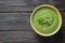 Fresh vegetable detox soup made of spinach in dish on wooden background, top view