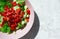 Fresh vegetable salad chopped sweet red paprika pepper, salad leaves and cucumber in pink plate on marble background, top view