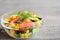 Fresh vegetable salad in a glass bowl. Salad with fresh cucumbers, tomatoes, corn, olive oil and lemon dressing. Closeup