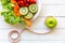 Fresh vegetable salad and healthy food for woman diet slimming with green apple, measure tap for weight loss on wood background