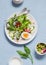 Fresh vegetable salad with tomatoes, radish, green herbs and boiled egg on a light blue stone background. Healthy Breakfast or