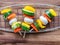 Fresh vegetable skewers for grilling with bell peppers, zucchini, mushroom on grill grid on wood table top