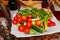 Fresh vegetables on a dish in the restaurant: cucumbers, cherry tomatoes, cilantro, green onions, bell peppers