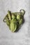 Fresh vegetables in a green string bag on a light gray background. Peking cabbage, artichokes and asparagus