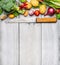 Fresh vegetables ingredients for cooking with used kitchen knife on white wooden background, top view, place for text.