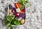 Fresh vegetables - red cabbage, radishes, carrots, potatoes, garlic, onions in a metal box on a light stone background. Healthy