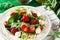 Fresh vegetarian salad with spinach, arugula, avocado slices, strawberries and mini mozzarella