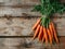 Fresh, vibrant carrots arranged on a rustic wooden table surface