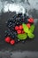 Fresh washed raspberries, blueberries, mint leaves with waterdrops. Organic berries on grey slate stone board.