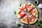 Fresh watermelon pizza salad with feta cheese, mint, salt and oil on stone background