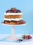 Fresh whipped cream and berries layer sponge cake on pink cake stand