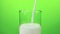 Fresh white milk pouring into drinking glass on chroma key green screen background, shooting with slow motion, diet and healthy