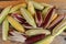 Fresh white, yellow and Siam Ruby Queen or Red corn on cobs on wooden table. Close up, top view. Fresh young corns ears with leave