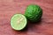 Fresh whole and half kaffir limes on wooden background