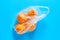 Fresh whole mandarins or oranges in polietilene bag on blue background. Fruit purchasing concept. Top view