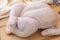 Fresh whole raw chicken on wooden cutting board