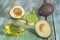 Fresh whole and sliced avocado and a bottle of oil on old green craked wooden background