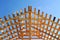 Fresh wooden yellow rafters on a background of blue sky. The construction of the pitched roof of a residential building. Bright