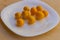 Fresh yellow caramel tomatoes on a white glossy plate