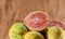 Fresh yellow guavas and broken in glass bowl on neutral background