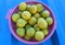 Fresh yellow lemons are in a basket isolated on a blue background. Bright Iron tin background with many Citrus limon