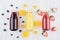 Fresh yellow orange, pink strawberry and violet blueberry juices in glass bottles with fruit ingredients on white wood board.