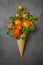 Fresh yellow-orange roses in a waffle cone on a grey background. Copy space, flat lay. Original packaging of the bouquet