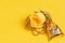 Fresh yellow rose decorated with beads and a gift bag on a yellow background