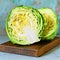 Fresh young cabbage on a wooden kitchen board for shredding on a blue background. Vegetables for cutting salad. Vegan food,