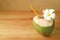 Fresh young coconut water in coconut shell with Plumeria flower on wooden table