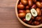 Fresh Ziziphus jujuba fruits in bowl on wooden table, top view. Space for text