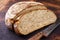 Freshly backed Farmhouse Bread sliced and offered on an old burnt cutting board