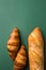 Freshly baked artisan croissants whole baguette with golden crust floury on dark green background. Top view. Minimalist modern