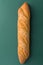 Freshly baked artisan whole baguette with golden crusty floury on dark green background. Top view. Minimalist