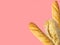 Freshly baked artisan whole french baguettes with golden crusty floury texture ciabatta on pink background. Poster banner