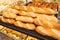 Freshly baked bread on bakery shelves. Bread diversity in bright light. Breads with golden crust. Loaves of bread assortment